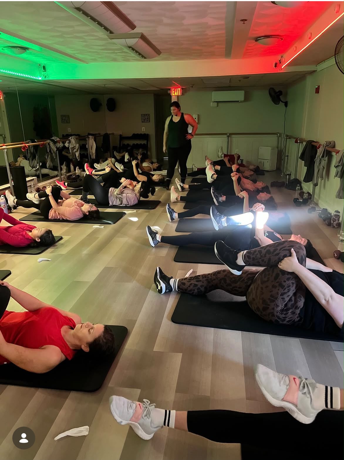 Women stretching on mats during a class led by a woman instructor
